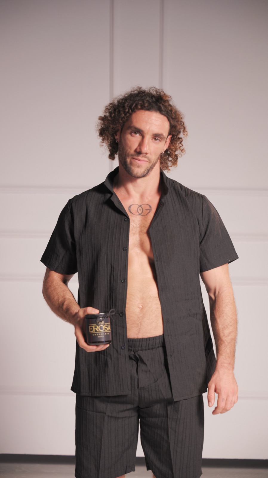 A man in a black shirt holding a jar of Erosa chocolate